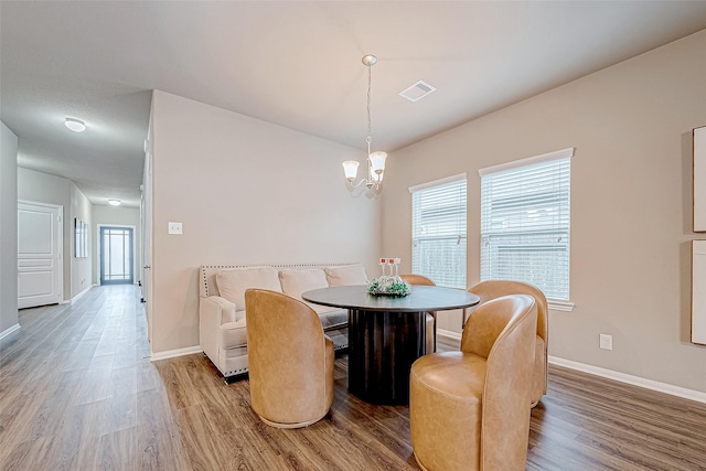 dining room with a notable chandelier, hardwood / wood-style flooring, and plenty of natural light