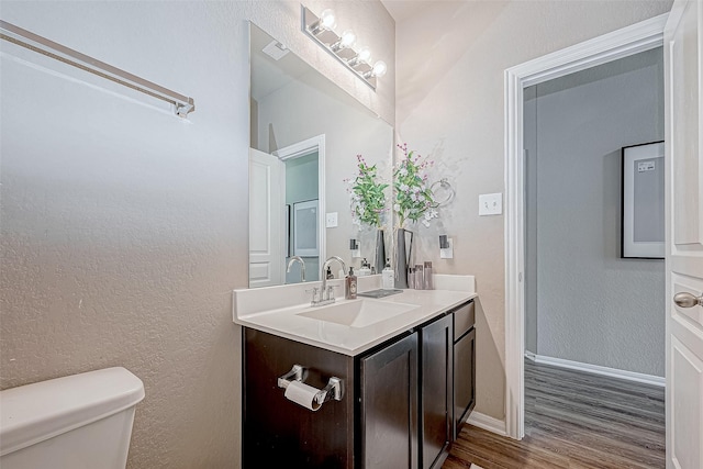 bathroom featuring vanity, wood-type flooring, and toilet