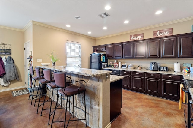 kitchen with a kitchen island, black fridge, dark brown cabinets, and a breakfast bar area