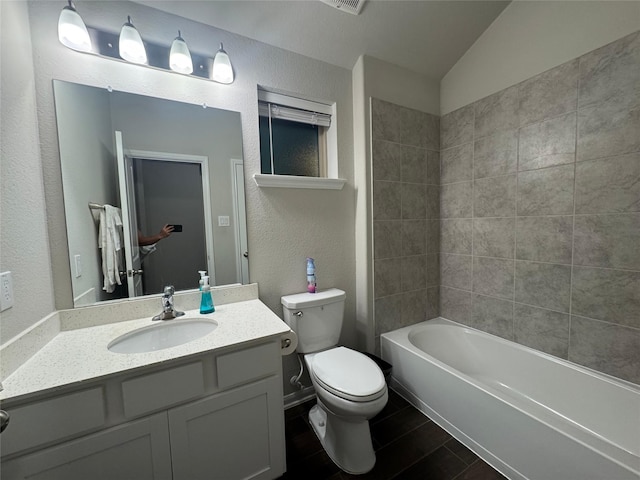 full bathroom featuring tiled shower / bath, vanity, toilet, and lofted ceiling