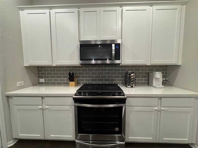 kitchen featuring stainless steel appliances, white cabinets, and decorative backsplash