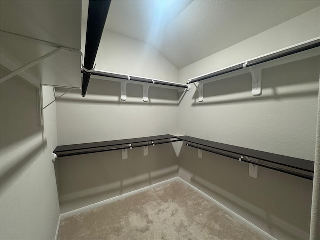 spacious closet with lofted ceiling and light colored carpet