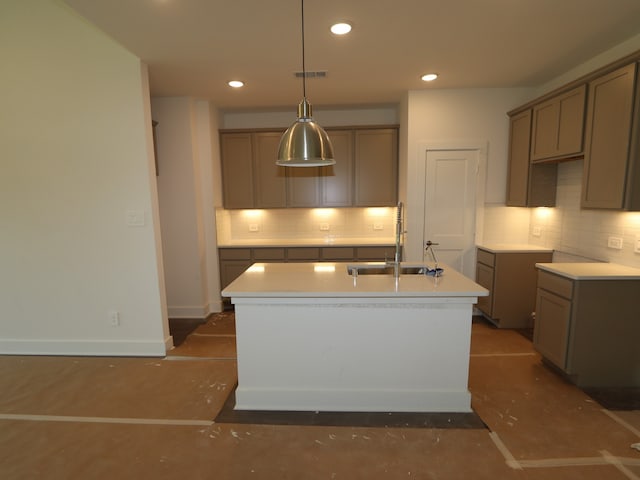 kitchen featuring visible vents, decorative backsplash, baseboards, a center island with sink, and a sink