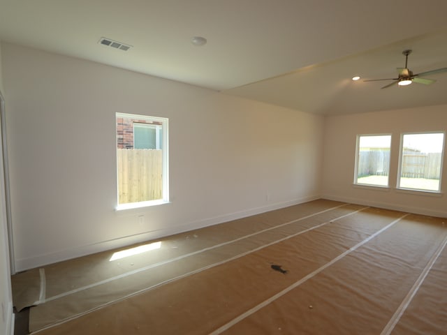 empty room with baseboards, ceiling fan, lofted ceiling, and visible vents