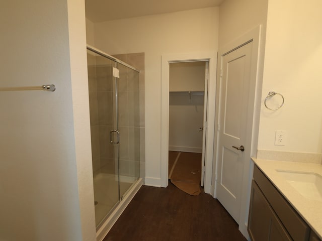 bathroom with vanity, wood finished floors, a spacious closet, and a shower stall