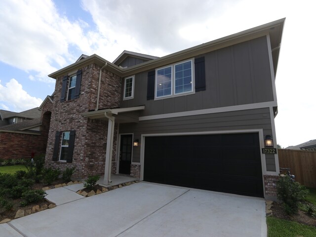 17322 Silver Birch Ct, New Caney, TX 77357 - view of front facade with an attached garage, board and batten siding, concrete driveway, and brick siding