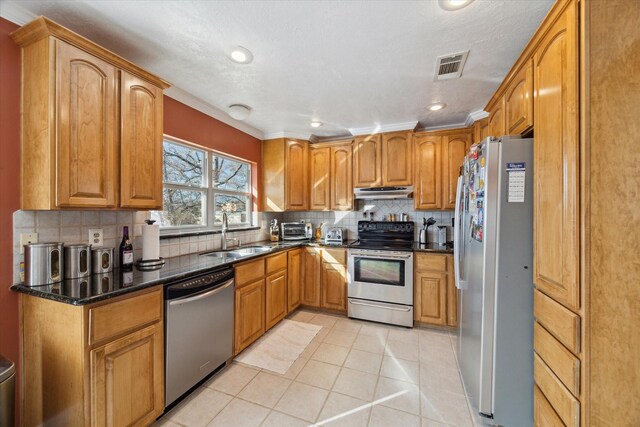 kitchen featuring sink, dark stone countertops, backsplash, light tile patterned floors, and stainless steel appliances