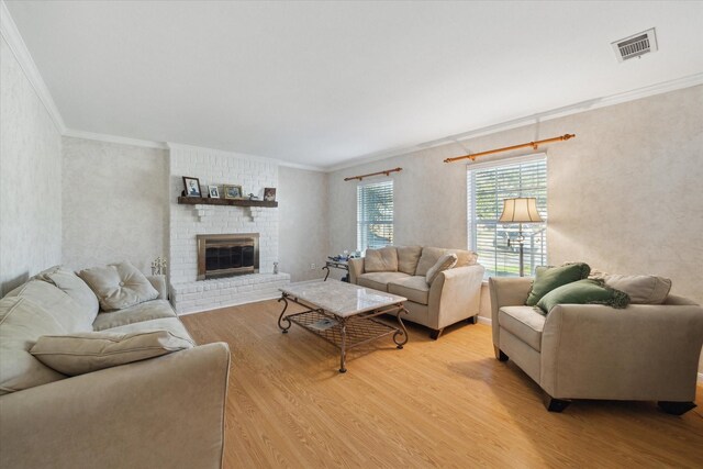 living room with ornamental molding, a brick fireplace, and light hardwood / wood-style flooring