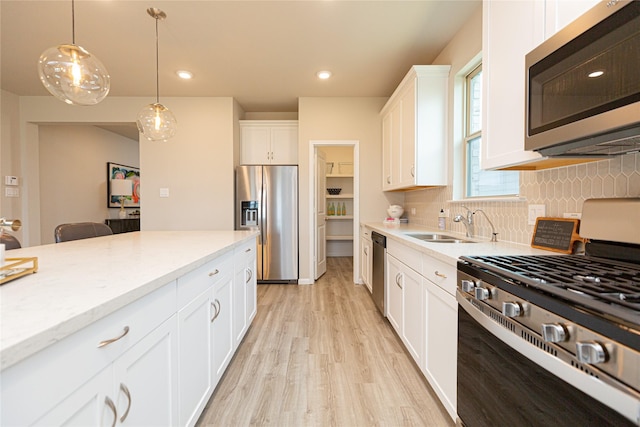 kitchen with tasteful backsplash, hanging light fixtures, stainless steel appliances, and white cabinets