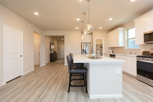 kitchen featuring tasteful backsplash, a center island, pendant lighting, stainless steel appliances, and white cabinets