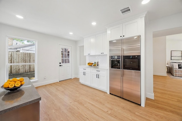 kitchen featuring white cabinetry, stainless steel appliances, stone countertops, and light hardwood / wood-style flooring