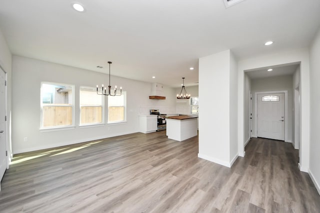 unfurnished living room with wood-type flooring and a notable chandelier