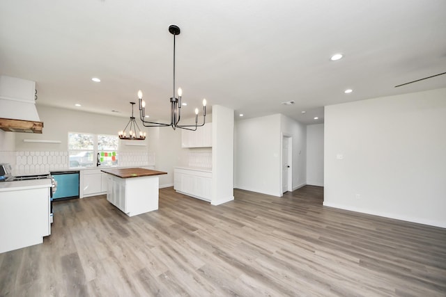 kitchen with pendant lighting, butcher block countertops, white cabinets, a center island, and stainless steel range