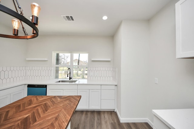 kitchen with sink, white cabinetry, dark hardwood / wood-style flooring, decorative backsplash, and stainless steel dishwasher