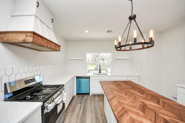 kitchen with premium range hood, sink, white cabinetry, decorative light fixtures, and stainless steel appliances