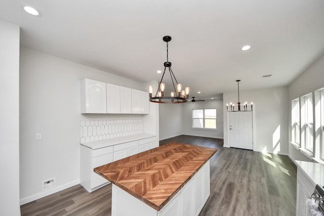 kitchen with dark wood-type flooring, white cabinetry, a center island, a notable chandelier, and decorative light fixtures