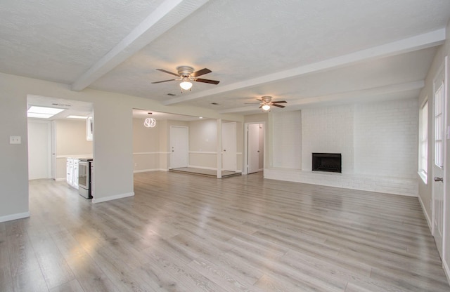 unfurnished living room featuring light hardwood / wood-style flooring, beam ceiling, a fireplace, and a textured ceiling