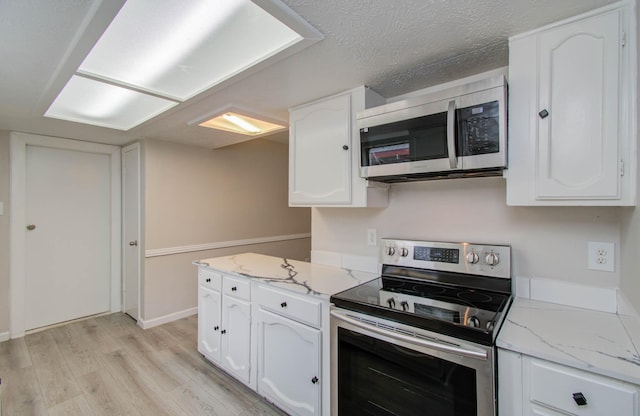 kitchen with white cabinetry, light hardwood / wood-style floors, a textured ceiling, and appliances with stainless steel finishes