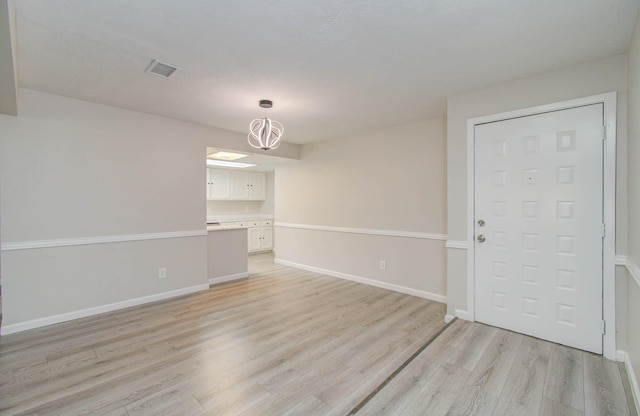 spare room with an inviting chandelier and light hardwood / wood-style flooring