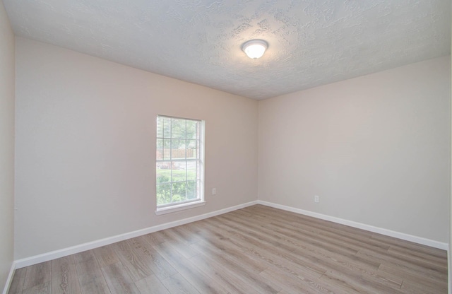 spare room featuring light hardwood / wood-style flooring and a textured ceiling