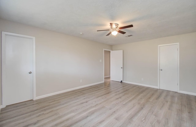 unfurnished room with ceiling fan, a textured ceiling, and light wood-type flooring