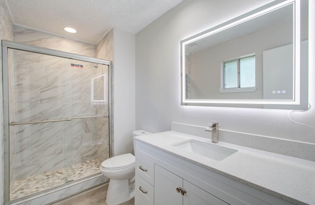 bathroom featuring vanity, an enclosed shower, a textured ceiling, and toilet