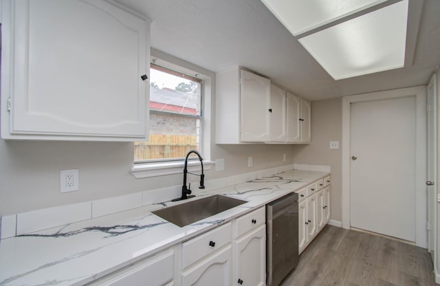 kitchen with white cabinetry, sink, stainless steel dishwasher, light hardwood / wood-style floors, and light stone countertops