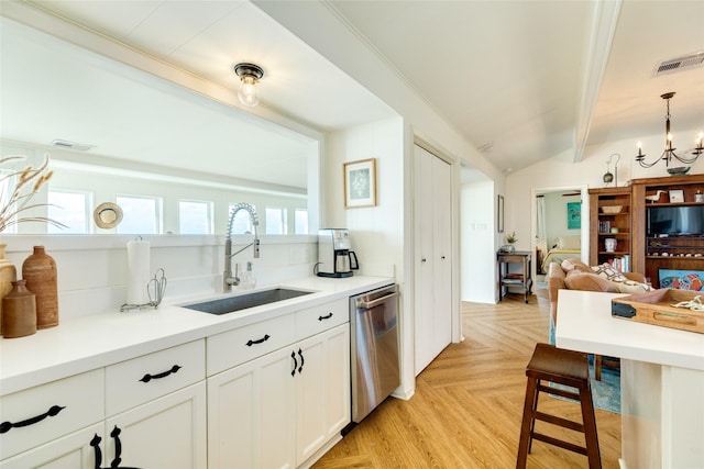 kitchen with sink, hanging light fixtures, dishwasher, light parquet floors, and white cabinets