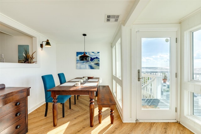 dining space with crown molding and light wood-type flooring