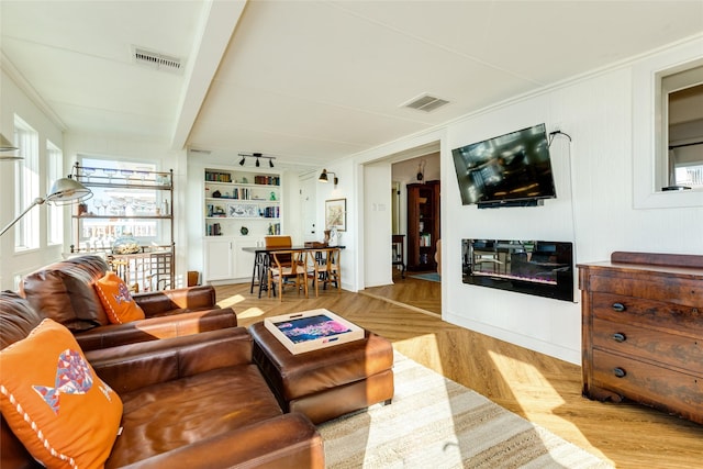 living room with light hardwood / wood-style flooring, built in shelves, and a wealth of natural light