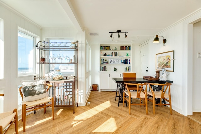 dining area featuring ornamental molding, rail lighting, and light hardwood / wood-style floors