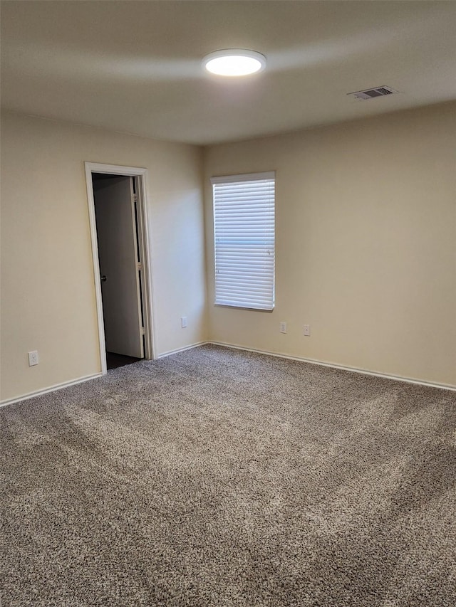 carpeted spare room featuring visible vents and baseboards