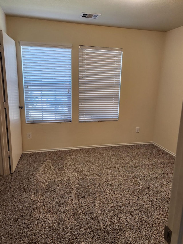 carpeted empty room featuring visible vents