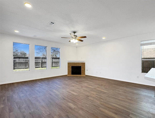 unfurnished living room with ceiling fan, dark wood-type flooring, a textured ceiling, and a fireplace