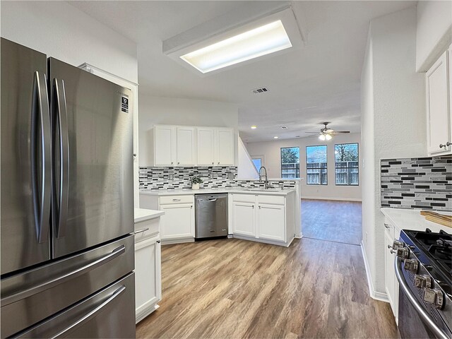 kitchen featuring white cabinetry, light hardwood / wood-style floors, kitchen peninsula, and appliances with stainless steel finishes