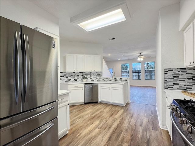 kitchen featuring appliances with stainless steel finishes, light countertops, a peninsula, and white cabinetry