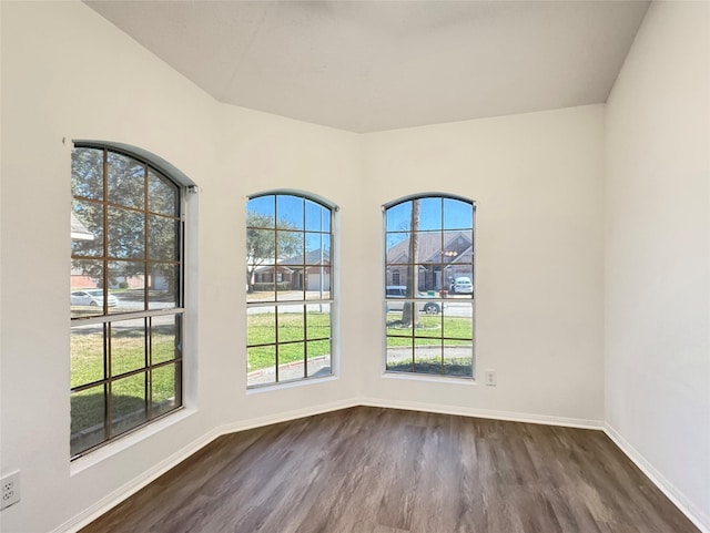 unfurnished dining area with dark wood-style flooring and baseboards