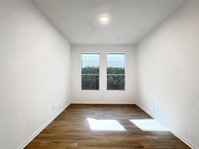 unfurnished room with baseboards and dark wood-type flooring