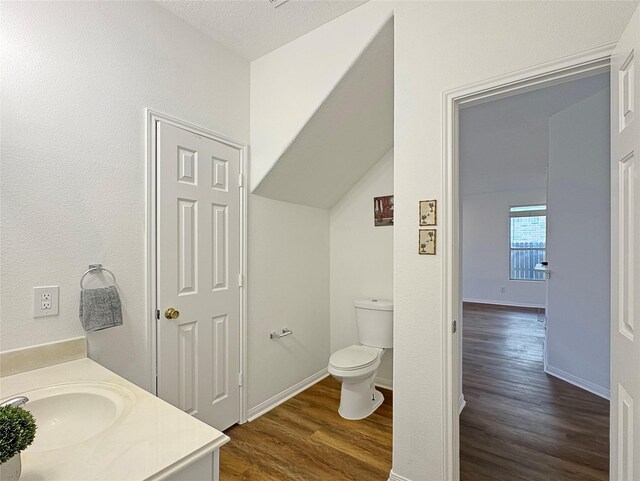 bathroom with lofted ceiling, vanity, toilet, and hardwood / wood-style floors