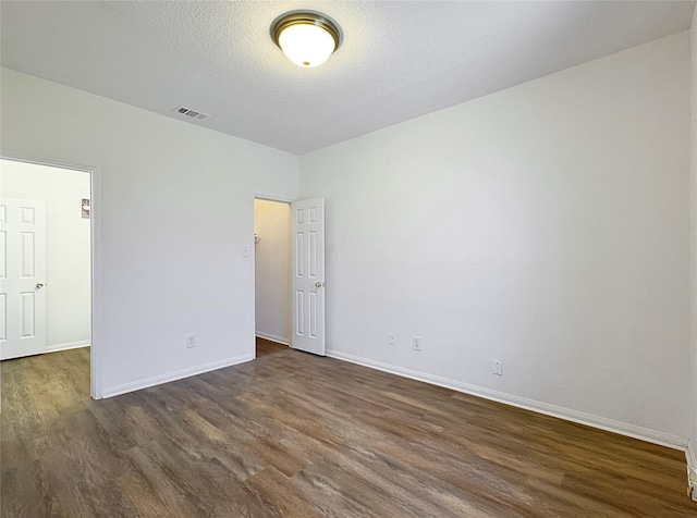 spare room with dark wood-type flooring and a textured ceiling