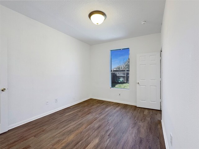 spare room featuring dark hardwood / wood-style floors and a textured ceiling