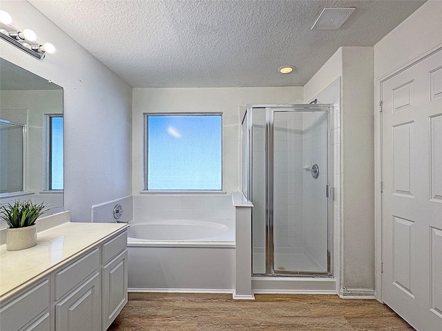 bathroom with vanity, hardwood / wood-style floors, plus walk in shower, and a textured ceiling