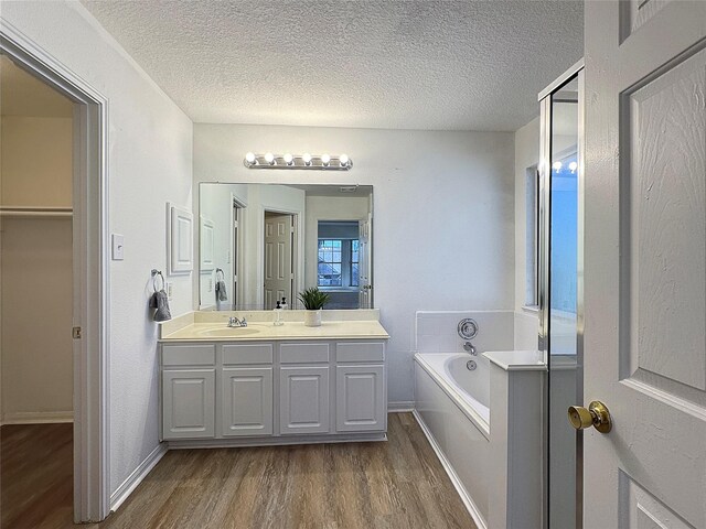 bathroom with hardwood / wood-style flooring, vanity, a bath, and a textured ceiling