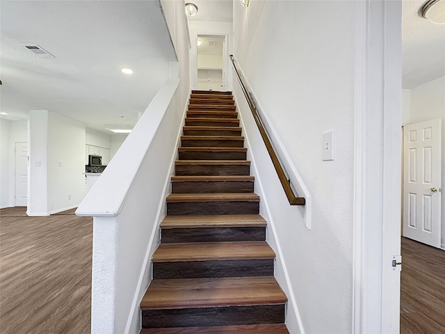 stairs with baseboards, visible vents, and wood finished floors