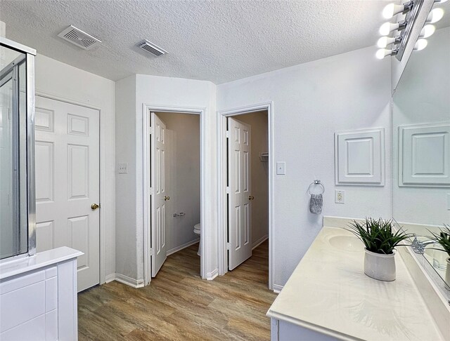 bathroom featuring vanity, hardwood / wood-style floors, a textured ceiling, and toilet