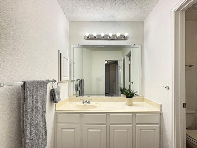 bathroom with vanity, toilet, and a textured ceiling