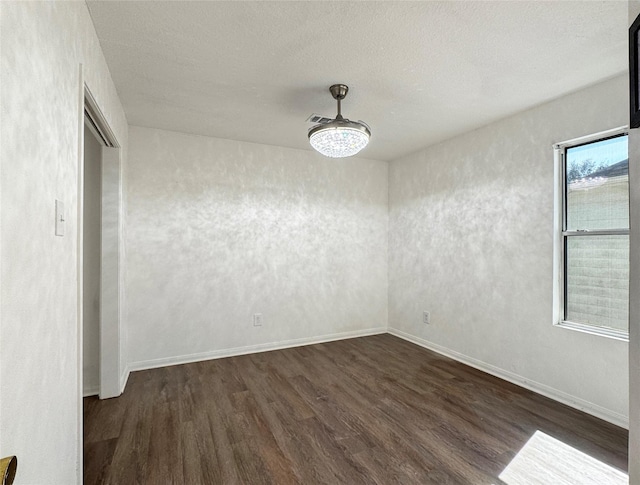 unfurnished room with dark wood-style floors, a textured ceiling, and baseboards