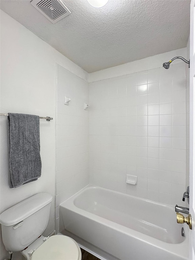 full bathroom with bathtub / shower combination, visible vents, a textured ceiling, and toilet