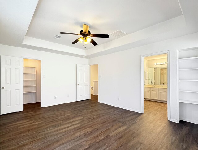 unfurnished bedroom featuring dark hardwood / wood-style flooring and a raised ceiling