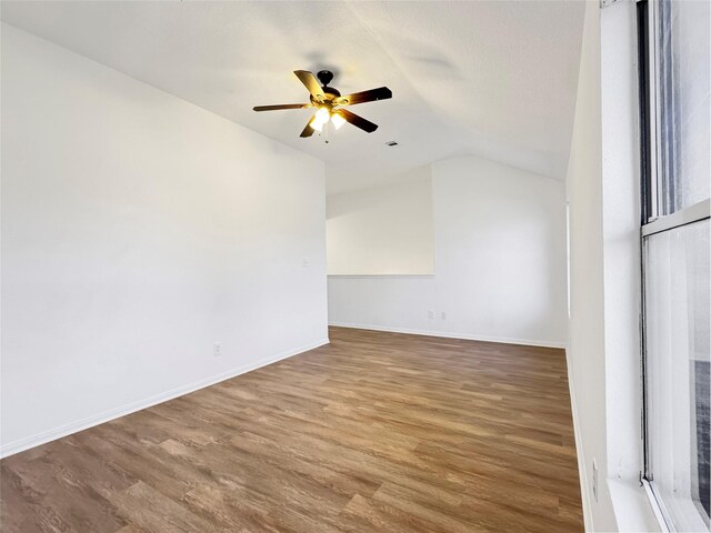 spare room featuring ceiling fan, baseboards, vaulted ceiling, and wood finished floors